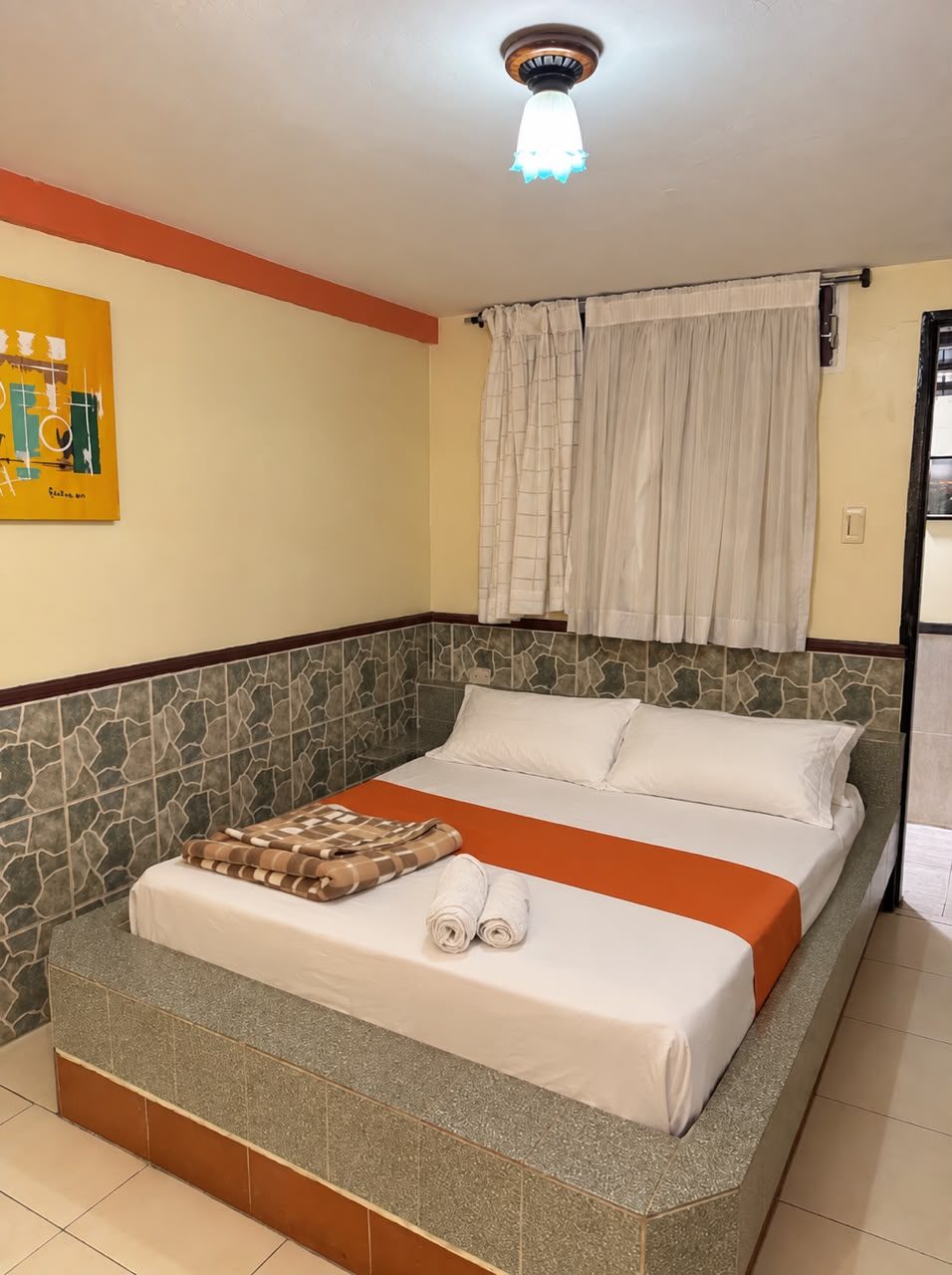 Habitación Full Equip con cama matrimonial, toallas enrolladas y paredes amarillas