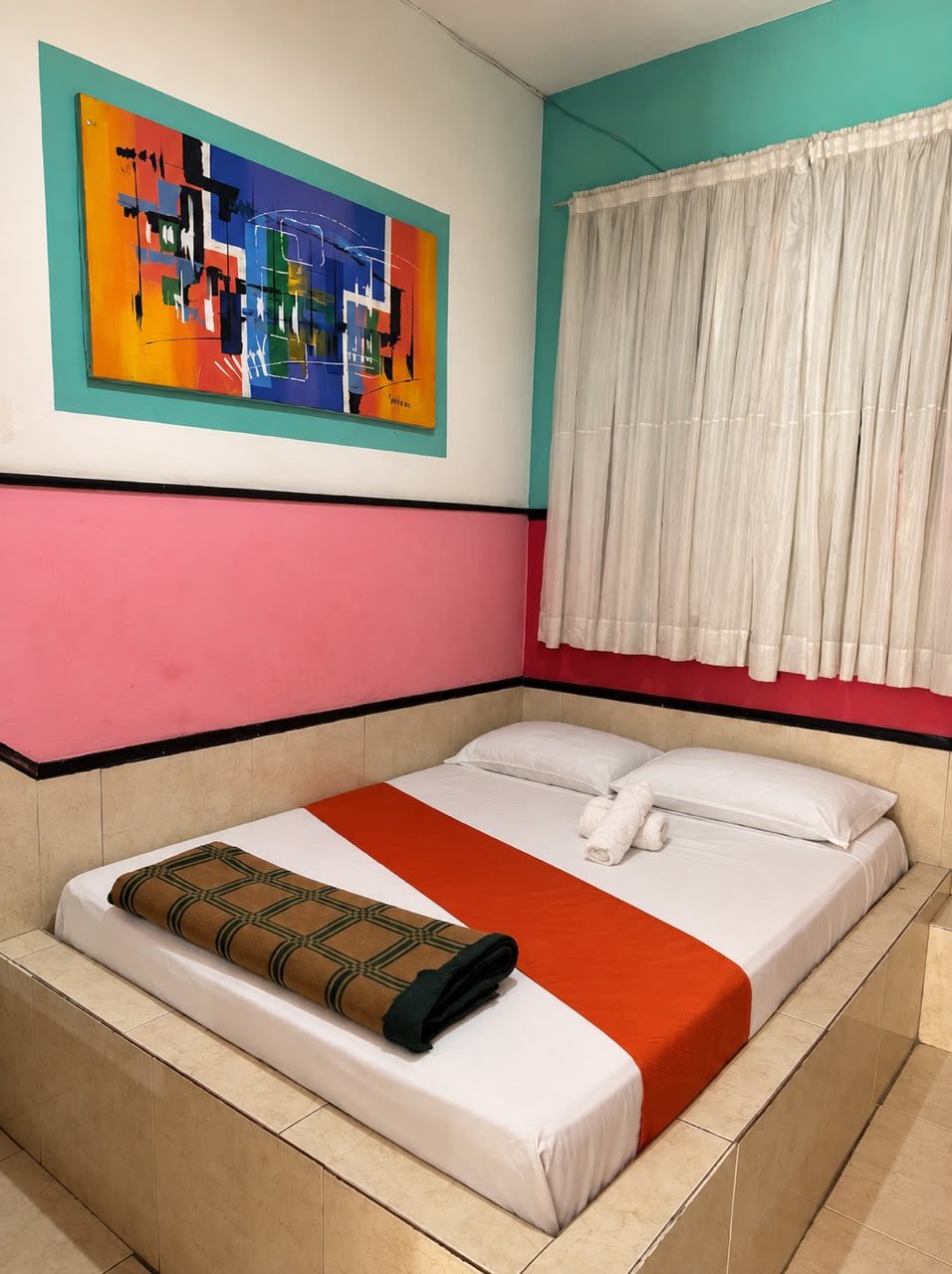Cama matrimonial con camino naranja bajo un cuadro abstracto, paredes rosa y turquesa